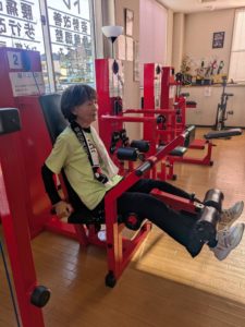 昭和町のジムで蹴り上げ訓を使い膝痛い改善トレーニングを行う80代女性